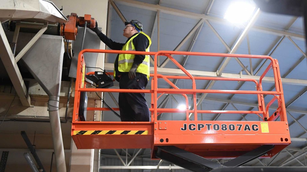 man working at height on a scissor lift in a warehouse