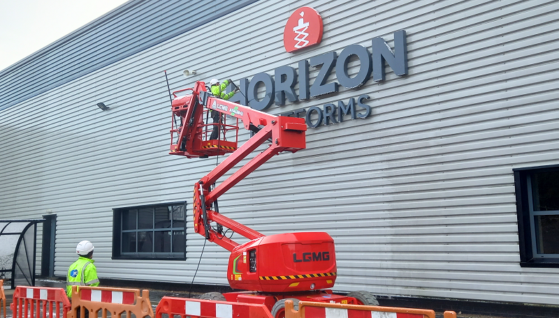 a man on a boom lift cleaning side of building