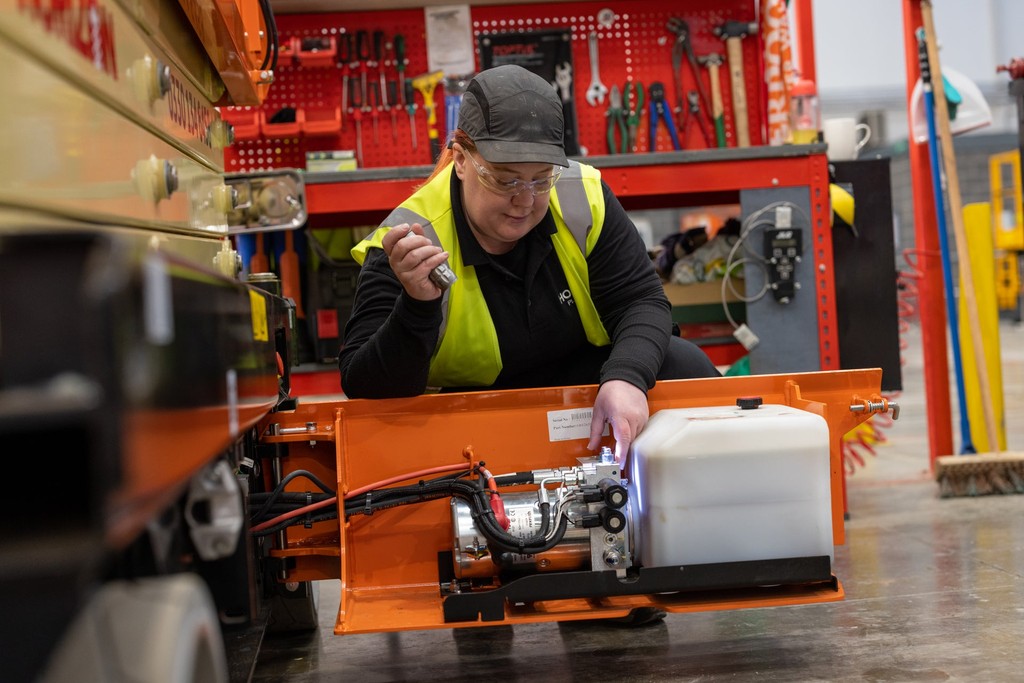 A worker inspecting a MEWP for problems or faults